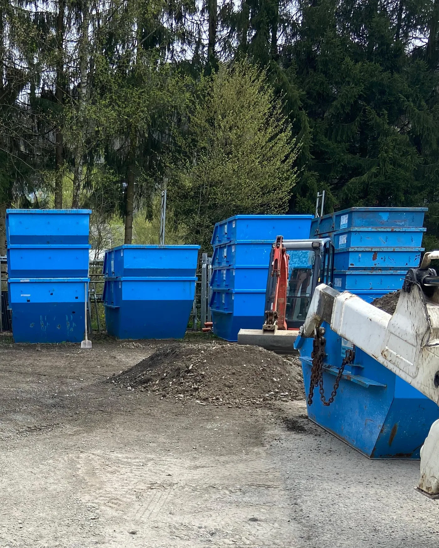 Betriebshof mit sechs blauen Absetzcontainern und Minibagger
